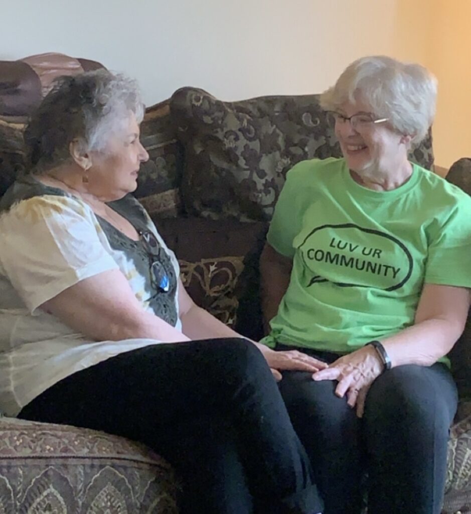 Two women sitting on a couch talking and smiling with each other